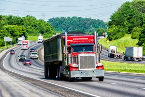 Red semi truck driving down a highway