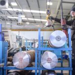 Engineer using crane to lift steel in factory