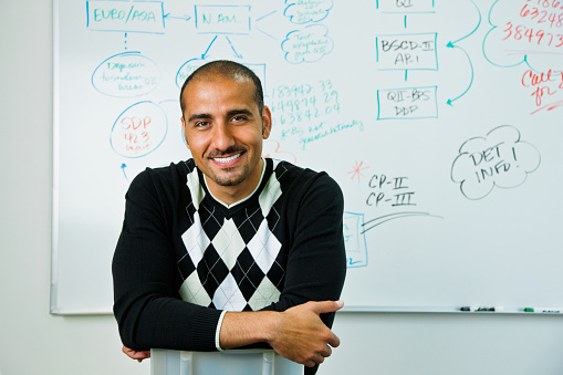 Middle Eastern man sitting near whiteboard