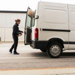 Side view of manual worker closing delivery van while standing on road