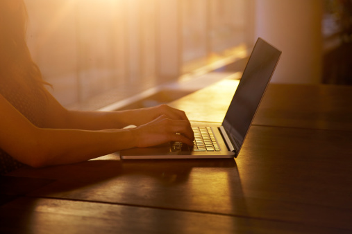 Woman typing as the sun sets behind her.