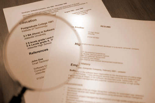 sepia toned selective focus shot of resume and magnifying glassPlease Note: All information on resume is fake
