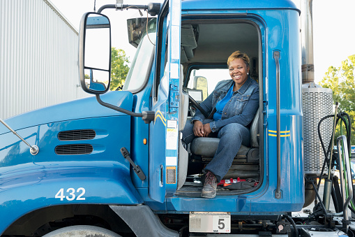 Smiling Black woman sitting in semi-truck