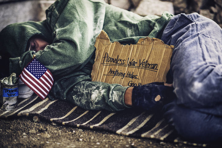 Homeless veteran sleeping on rug on street