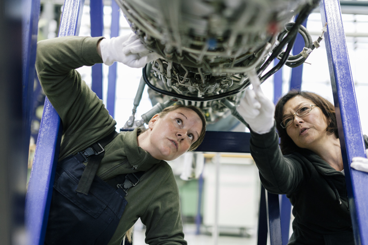 Female mechanics or engineers examining aircraft engine
