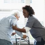 Home healthcare worker helps senior man with walker